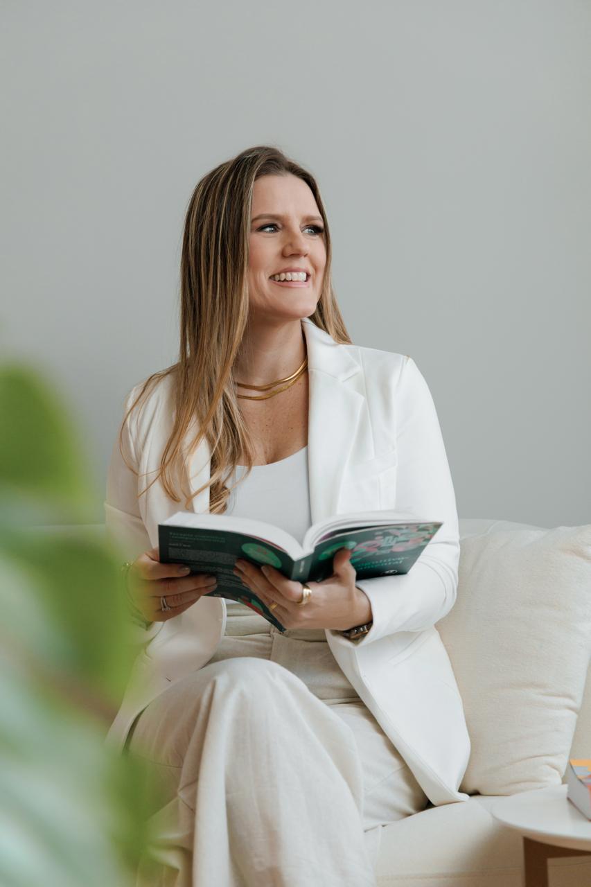 Patrícia Flemming com livro aberto, representando sua formação continuada em Terapia Cognitivo-Comportamental